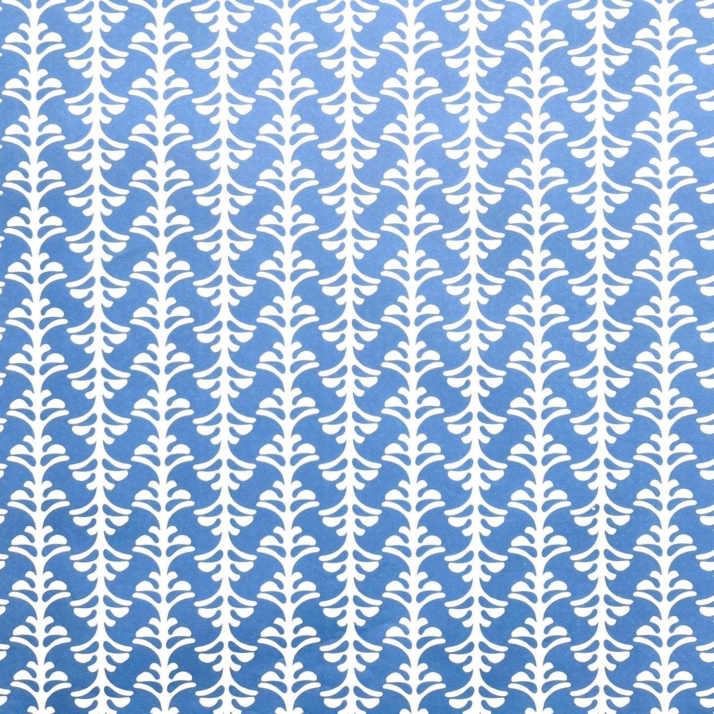 wrapping paper by Otto Editions with a cut-out palm design in white on a sky blue background.