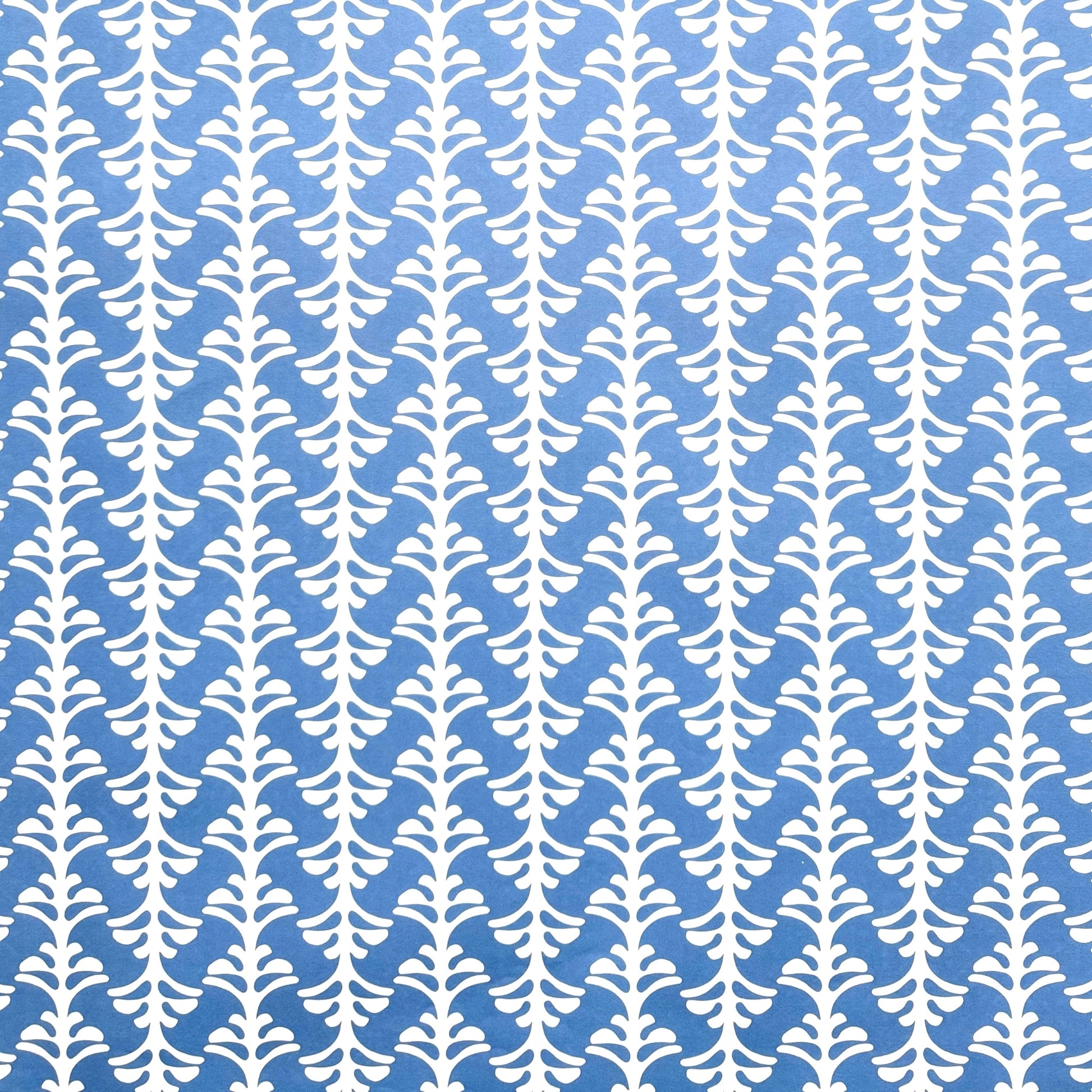 wrapping paper by Otto Editions with a cut-out palm design in white on a sky blue background.