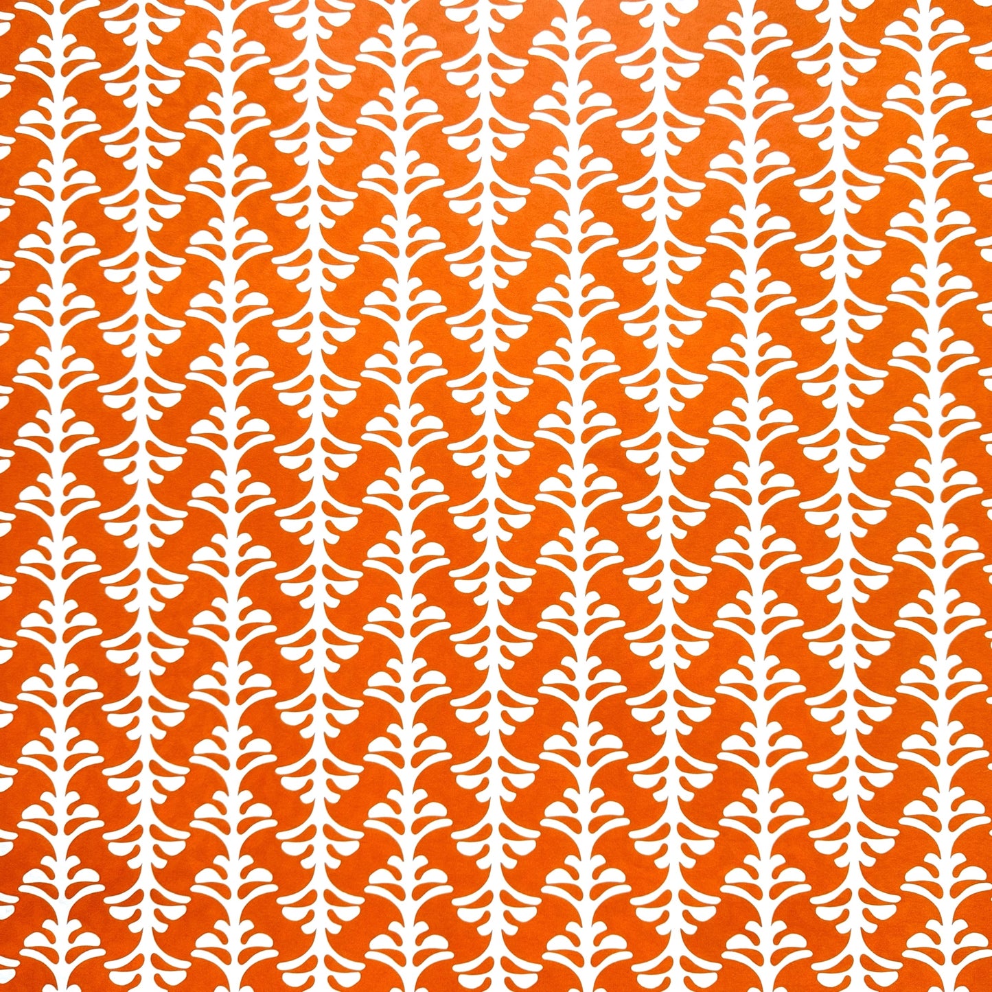 wrapping paper by Otto Editions with a cut-out palm design in white on a spice orange background.