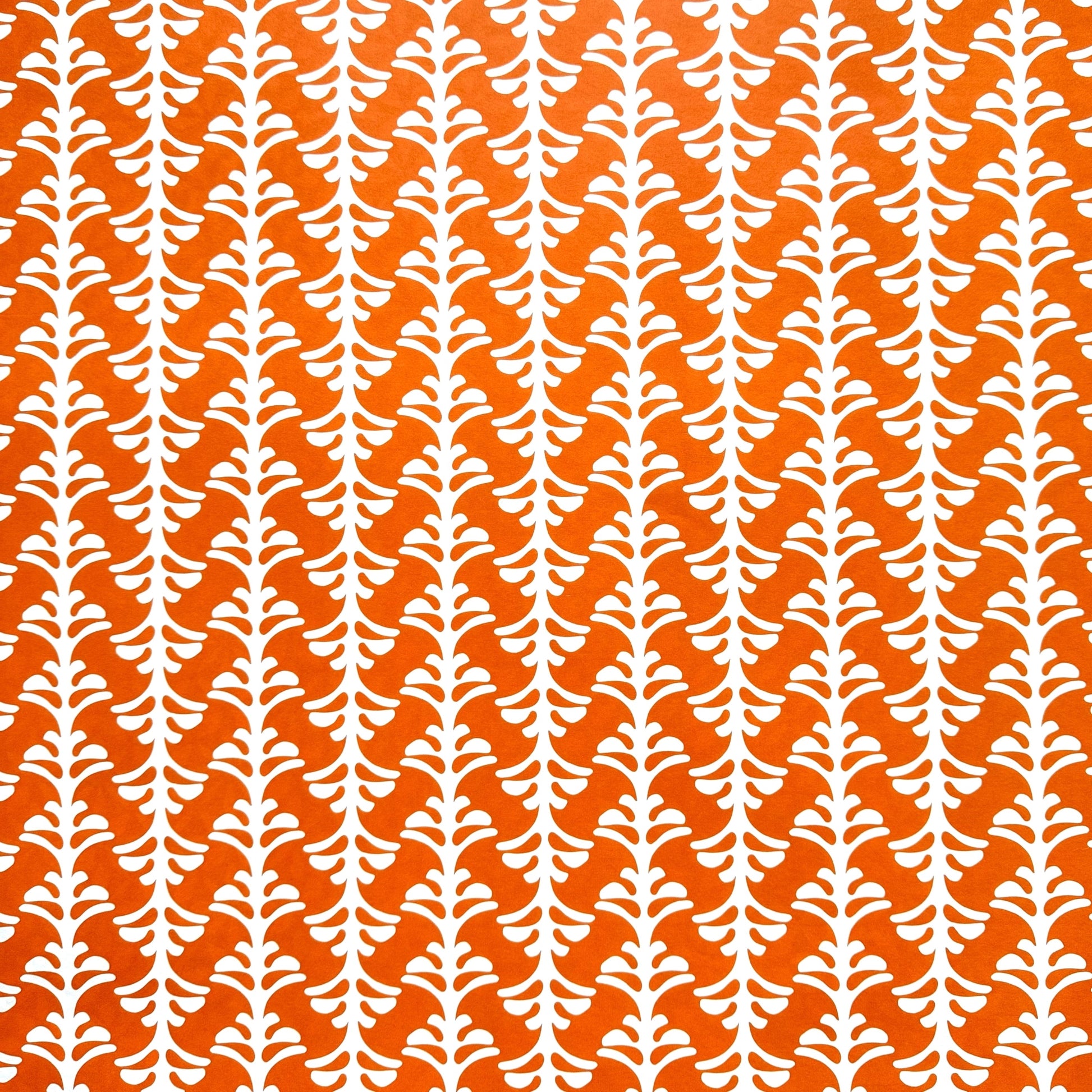 wrapping paper by Otto Editions with a cut-out palm design in white on a spice orange background.
