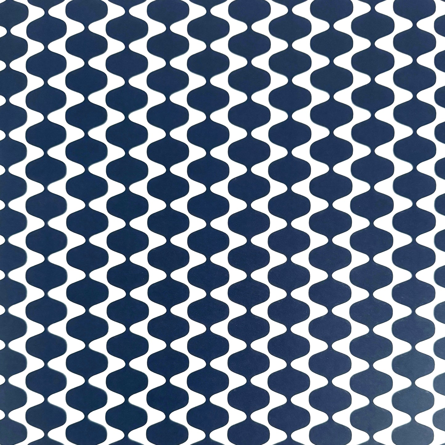 wrapping paper by Otto Editions with a cut-out wavy design in white on an indigo background.