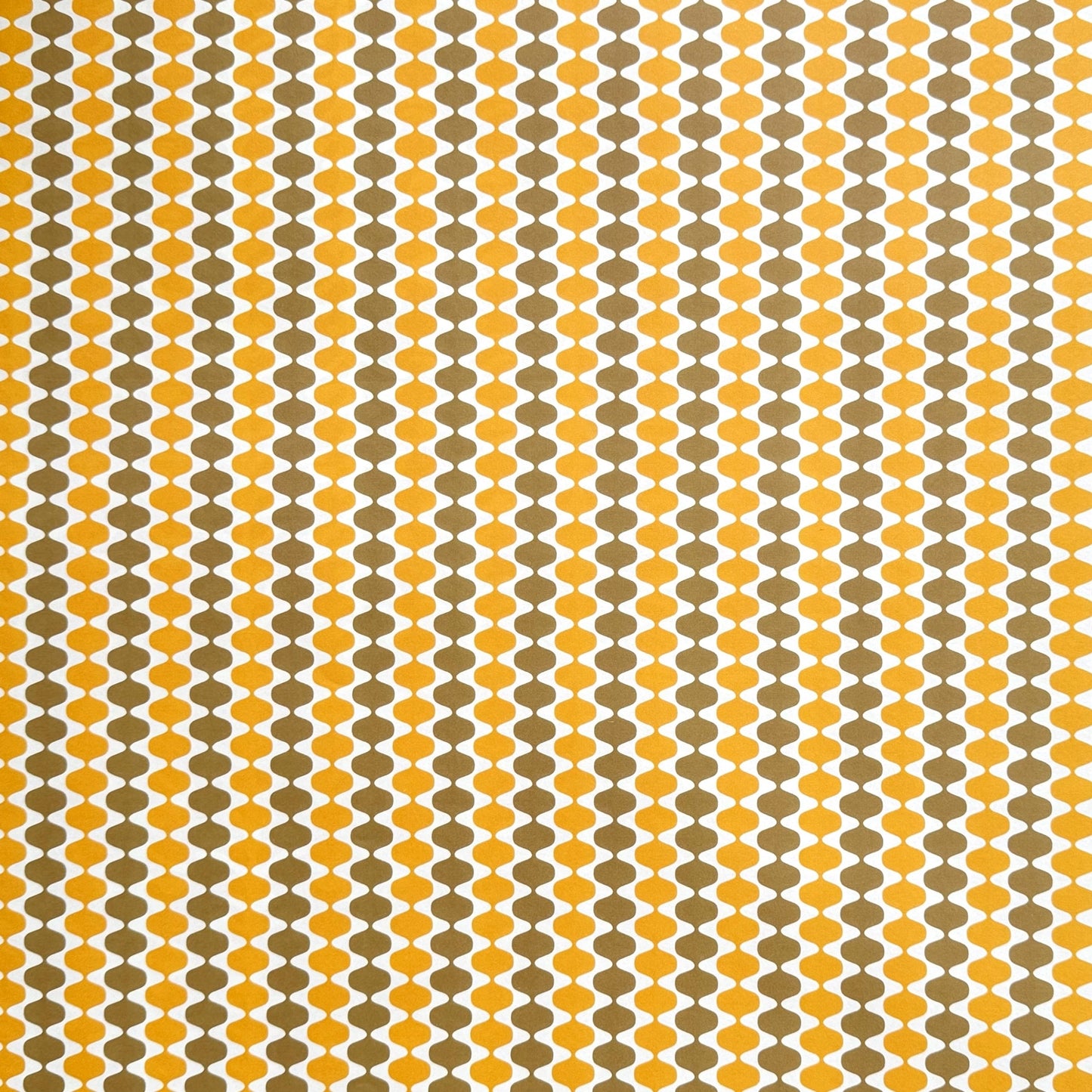 wrapping paper by Otto Editions with a cut-out wavy design in white on a yellow and gold background.