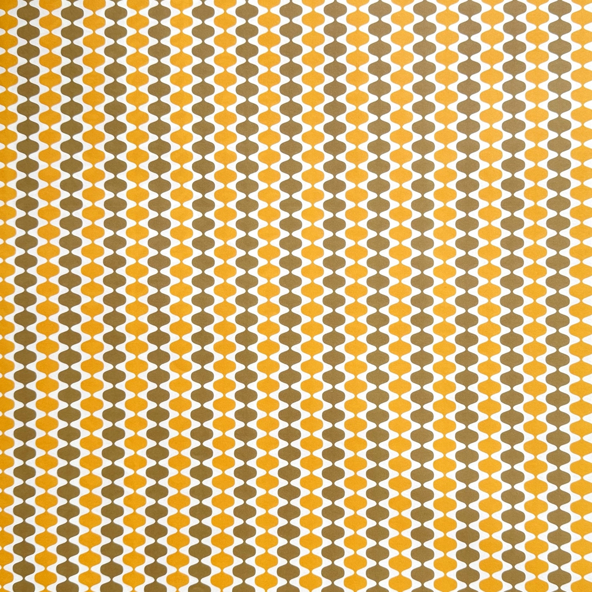 wrapping paper by Otto Editions with a cut-out wavy design in white on a yellow and gold background.