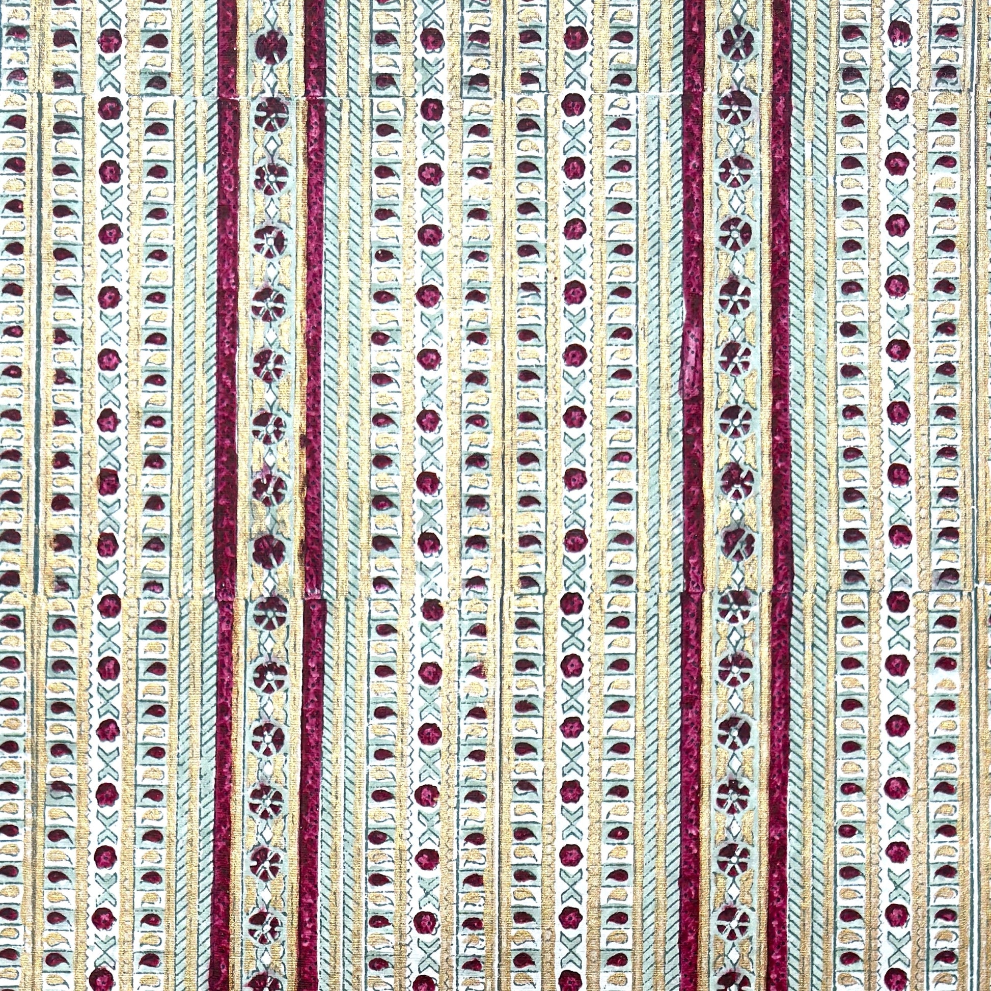 Hand block printed wrapping paper with a striped design in red, green and gold.