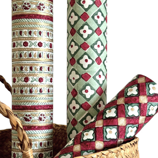 Hand block printed wrapping paper with a striped design in red, green and gold. Close up, pictured alongside other designs