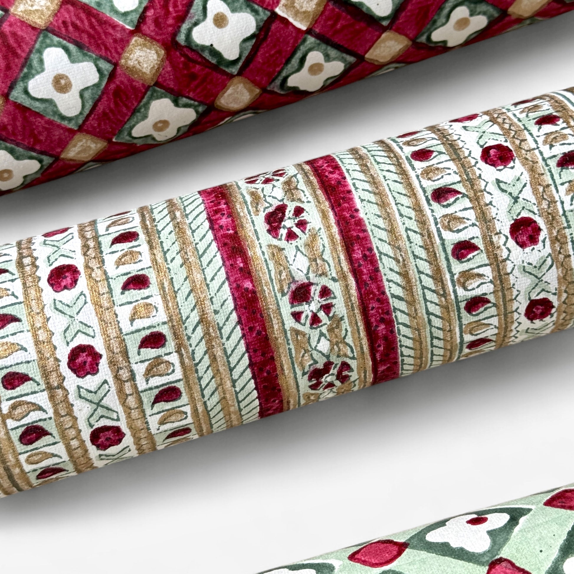 Hand block printed wrapping paper with a striped design in red, green and gold. Close up