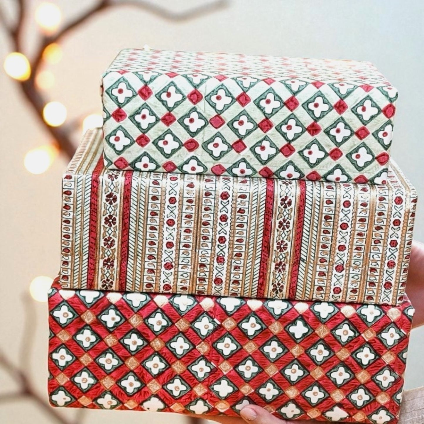 Hand block printed wrapping paper with a floral checked pattern in red, green and gold. Pictured wrapped alongside other presents