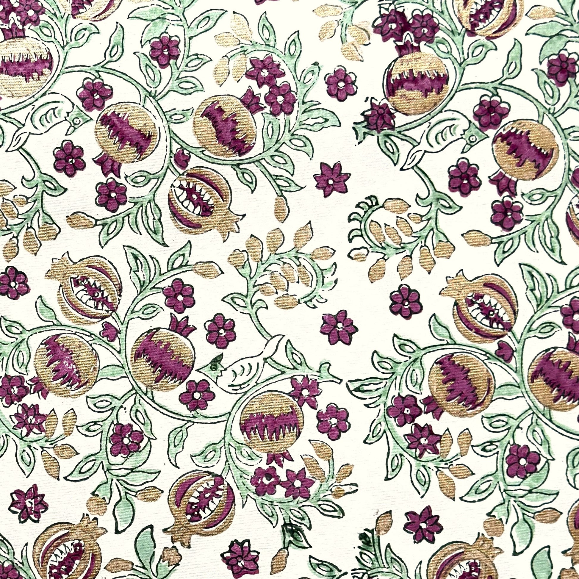 Hand block printed wrapping paper with a pattern of pomegranates in cherry red, green and gold.