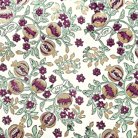 Hand block printed wrapping paper with a pattern of pomegranates in cherry red, green and gold.