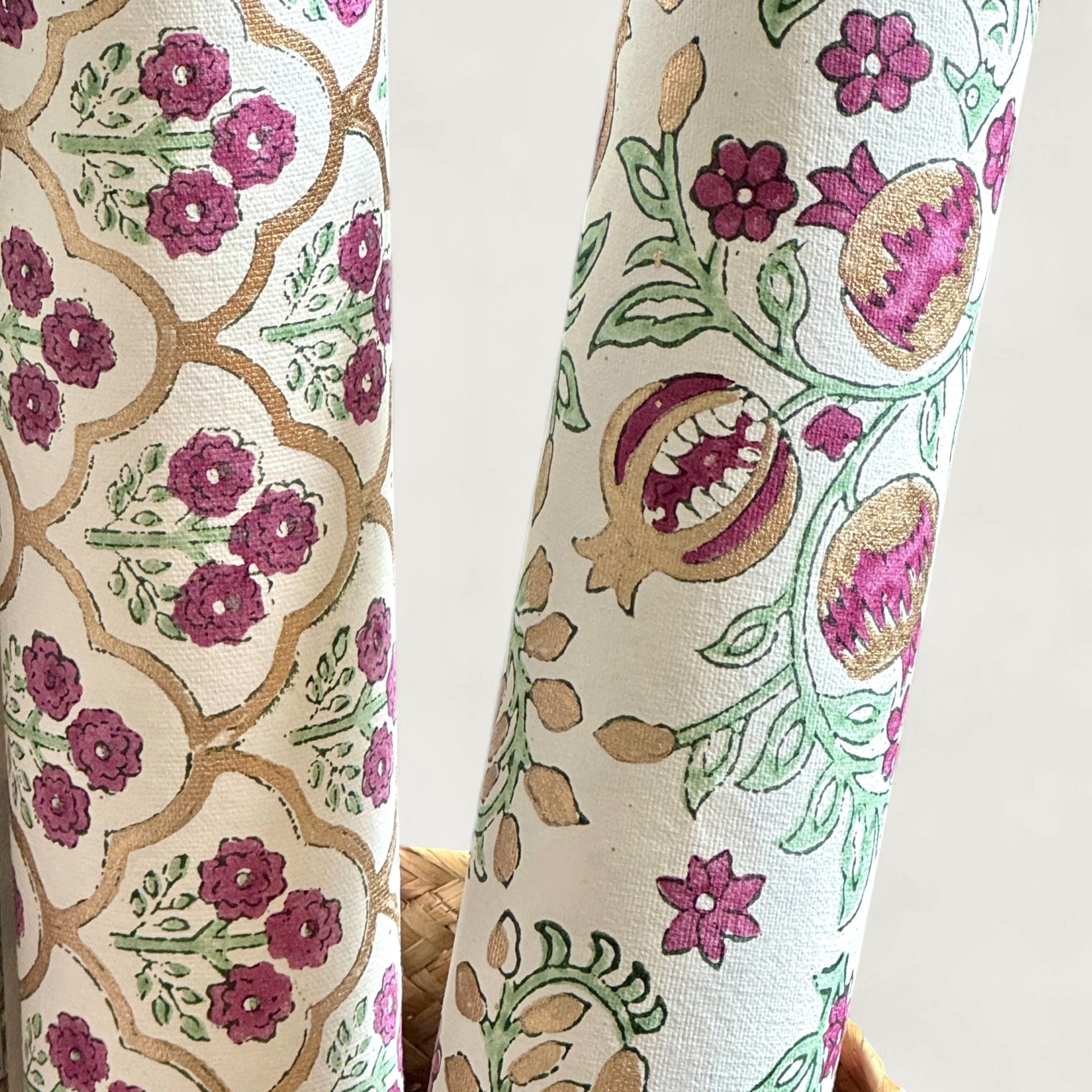 Hand block printed wrapping paper with a pattern of pomegranates in cherry red, green and gold. Close up