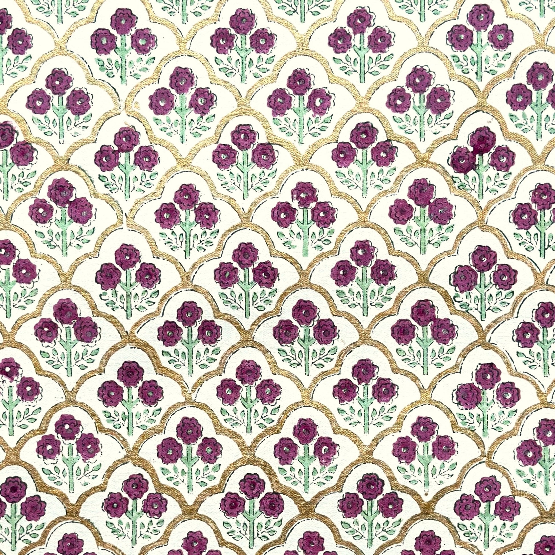 Hand block printed wrapping paper with a trellis pattern with flowers in cherry red, green and gold.