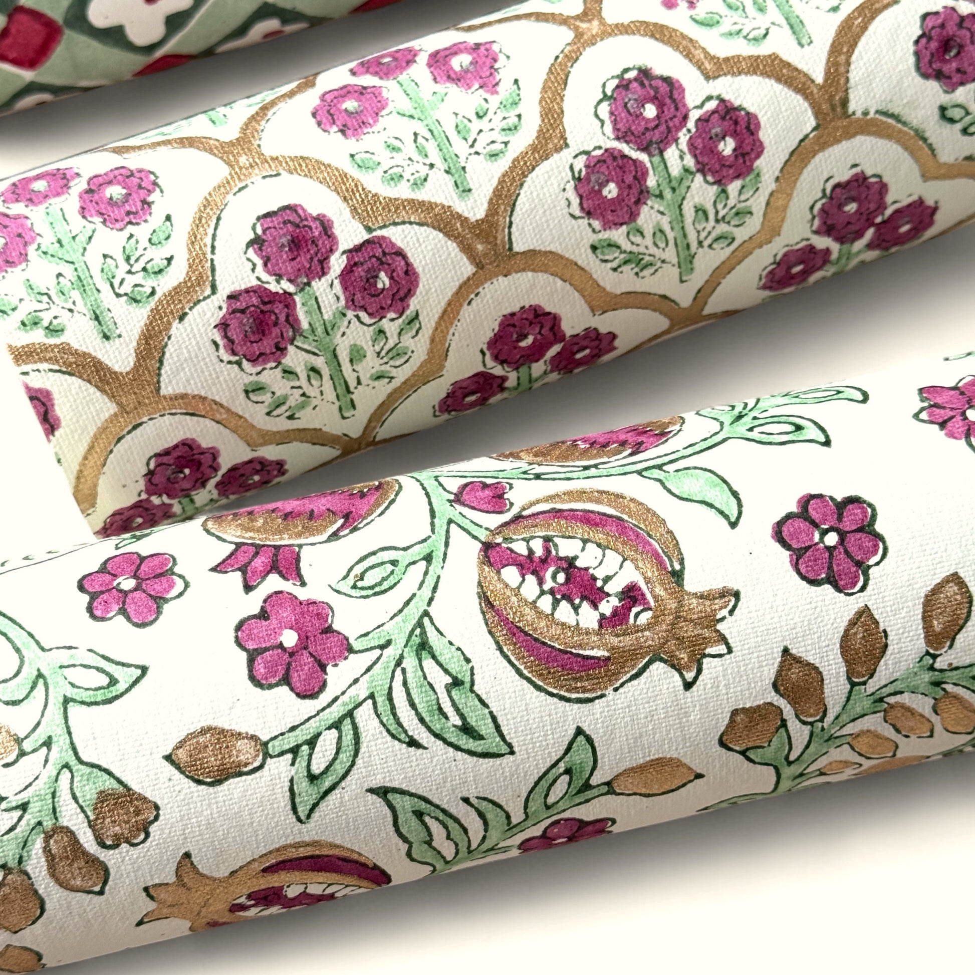 Hand block printed wrapping paper with a trellis pattern with flowers in cherry red, green and gold. rolled