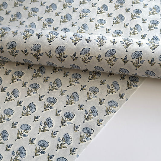 a hand block printed sheet of wrapping paper with a ditsy floral print in soft blue
