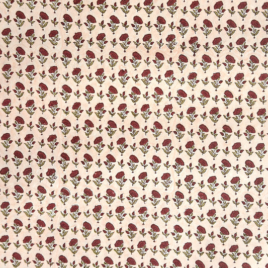 a sheet of hand block printed paper with a ditsy floral design in red and green on pink background