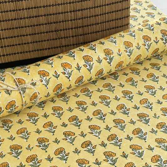 a sheet of hand block printed wrapping paper with a ditsy floral flower design in yellow