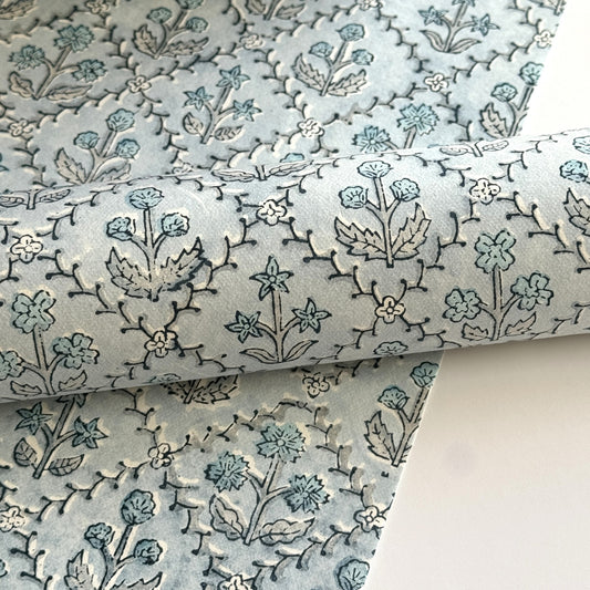 a sheet of hand block printed wrapping paper with a floral lattice design in soft blue
