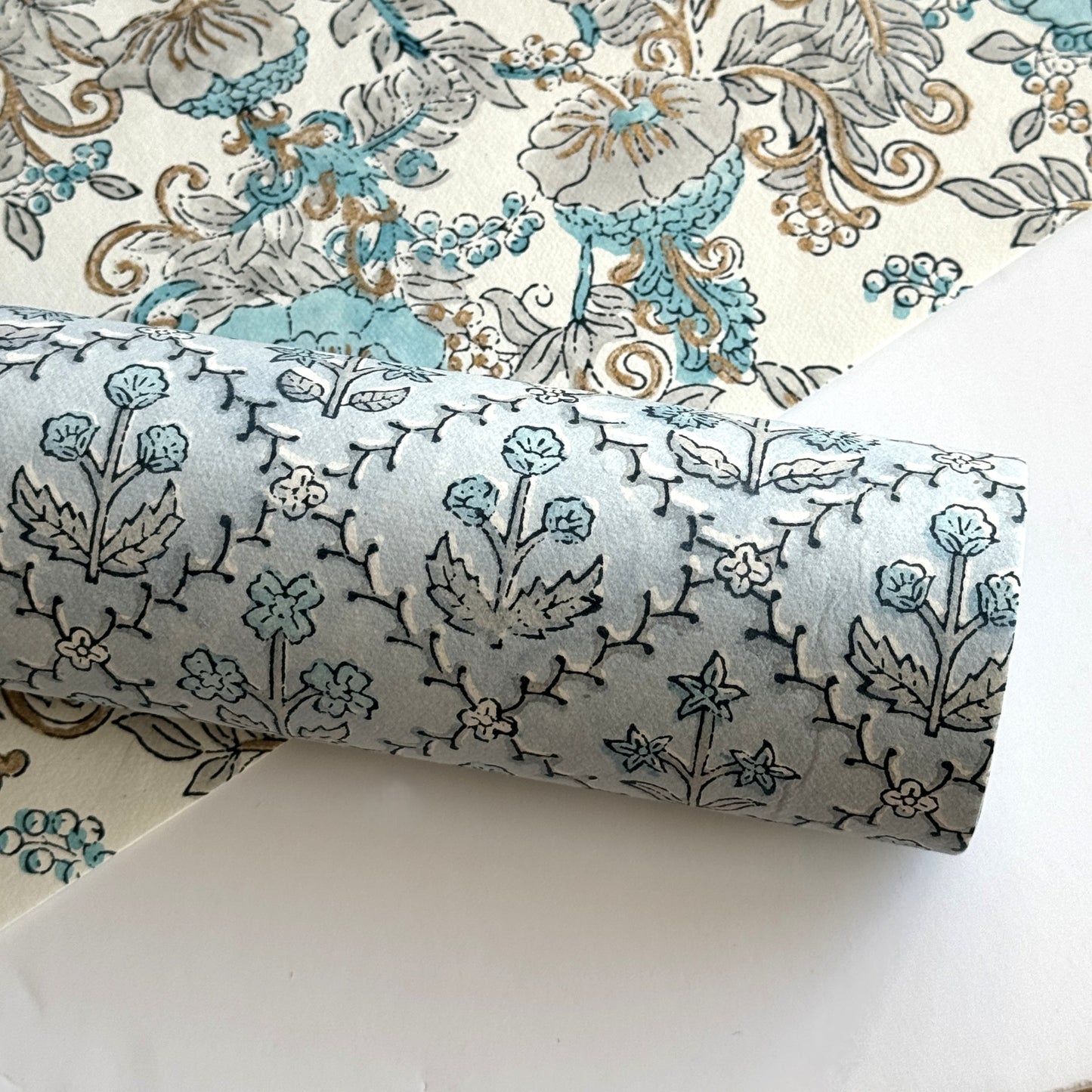 a sheet of hand block printed wrapping paper with a floral lattice design in soft blue