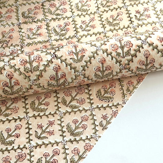 a sheet of hand block printed wrapping paper with a floral trellis design in coral pink and sage green