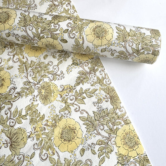 a sheet of hand block printed wrapping paper with a wild rose pattern in buttermilk yellow, moss green and gold