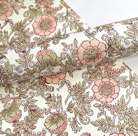 a hand block printed sheet of wrapping paper with a wild rose design in coral, moss green on a white background