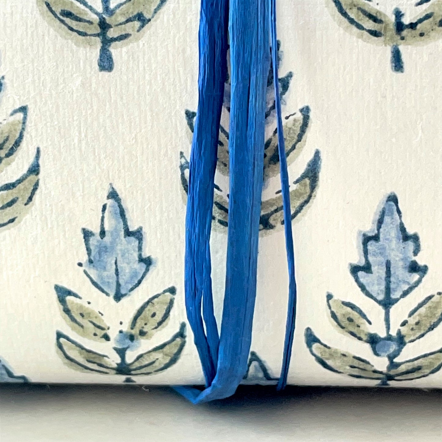 Wrapping paper with block print small flower motif in blue and grey-green, white background by Paper Mirchi