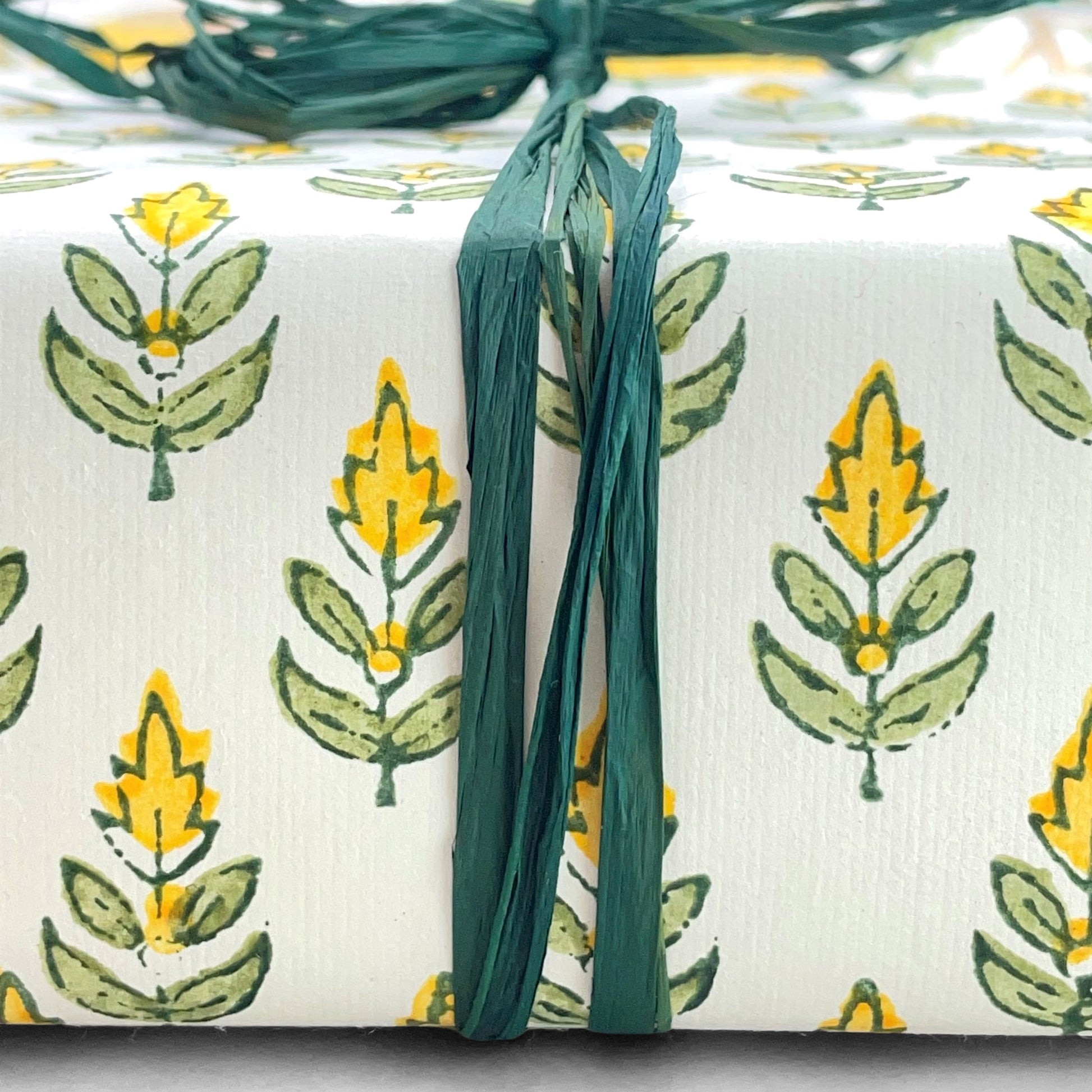 Wrapping paper with block print small flower motif in yellow and green, white background by Paper Mirchi