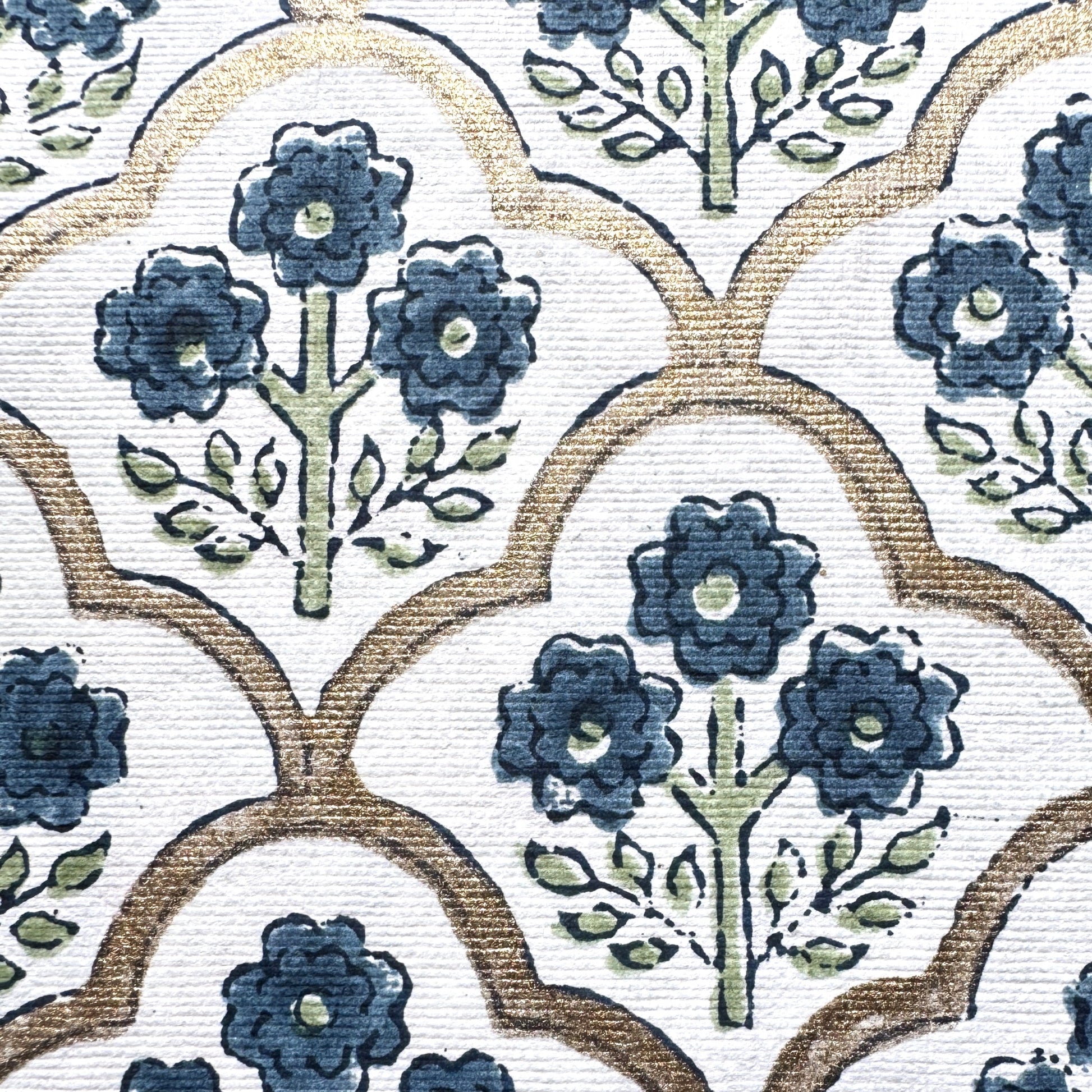 hand block printed wrapping paper with a small flower design in indigo and green surrounded by a gold trellis design. By Paper Mirchi. Close up