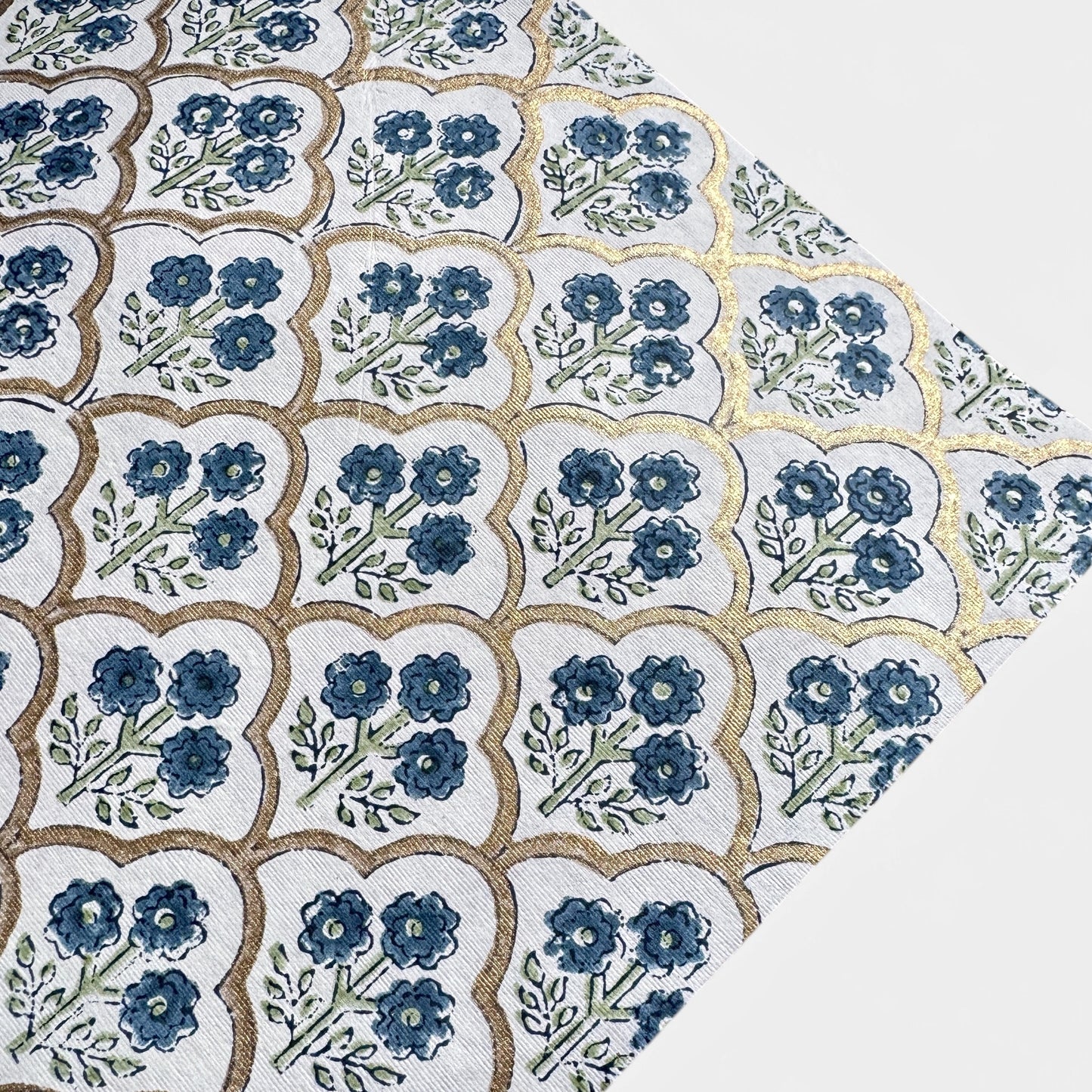 hand block printed wrapping paper with a small flower design in indigo and green surrounded by a gold trellis design. By Paper Mirchi