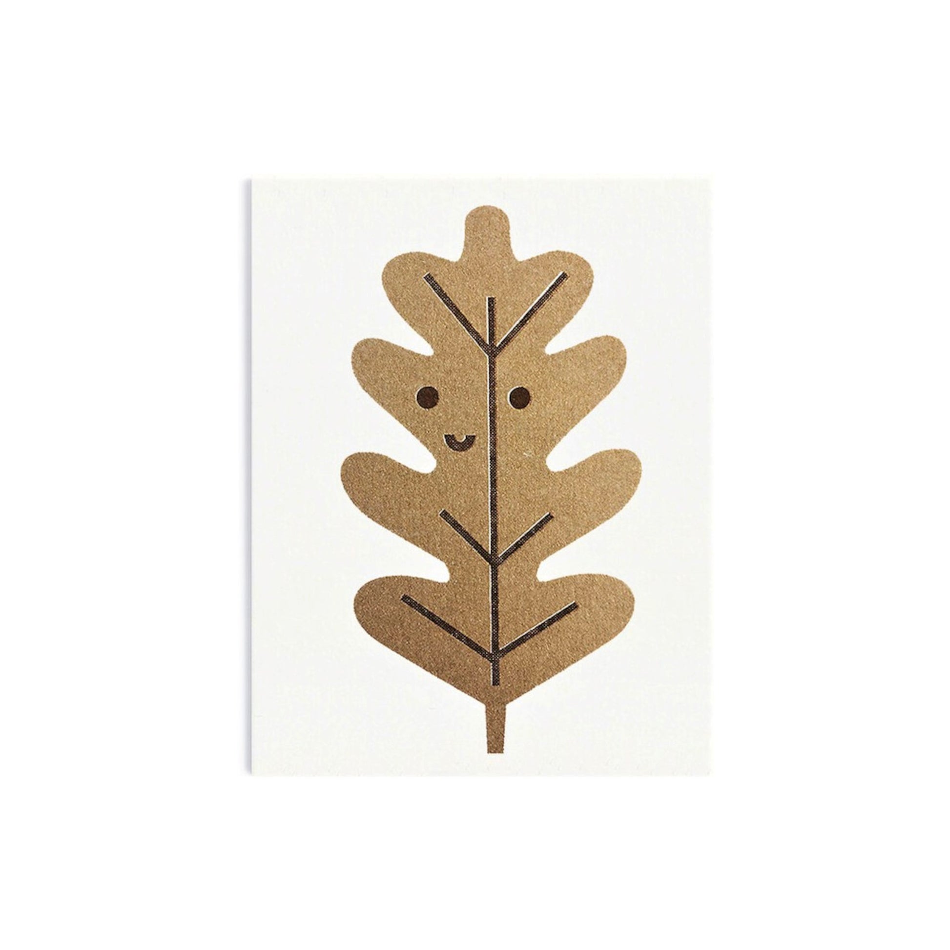 Mini greetings card with an image of a gold oak leaf with a smily face. By Scout Editions.