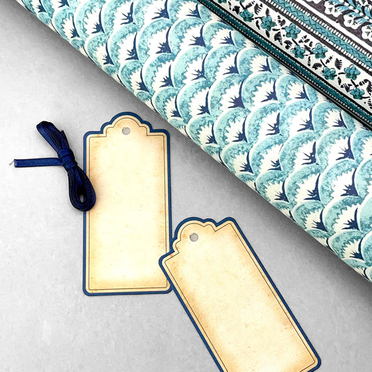 set of 4 vintage style gift tags by Grafiche Tassotti. Rectangular with sepia colour paper and navy border. Presented with navy ribbon. Pictured alongside rolled Italian wrapping paper