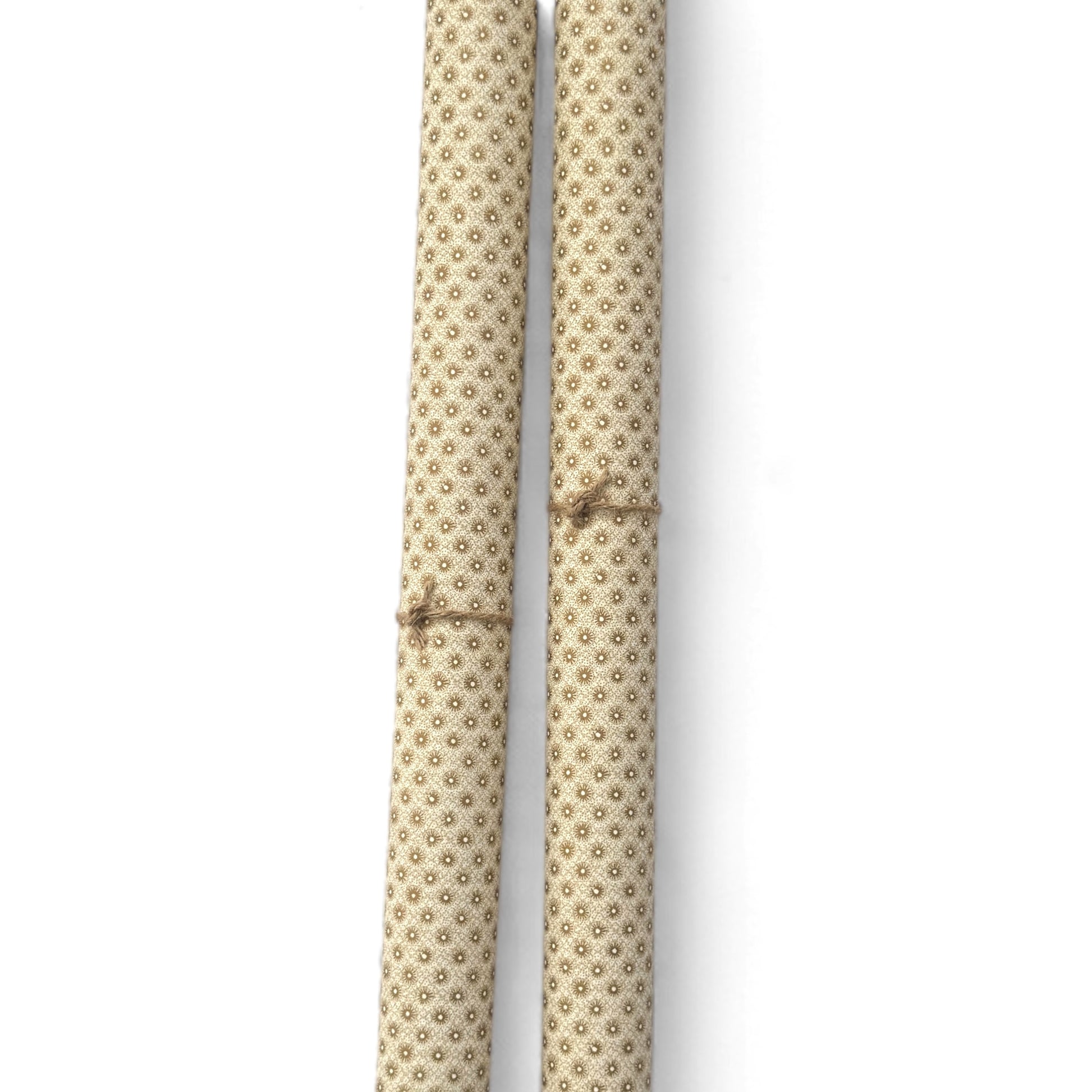 a sheet of italian wrapping paper with gold snowflakes on a cream backdrop. Pictured rolled