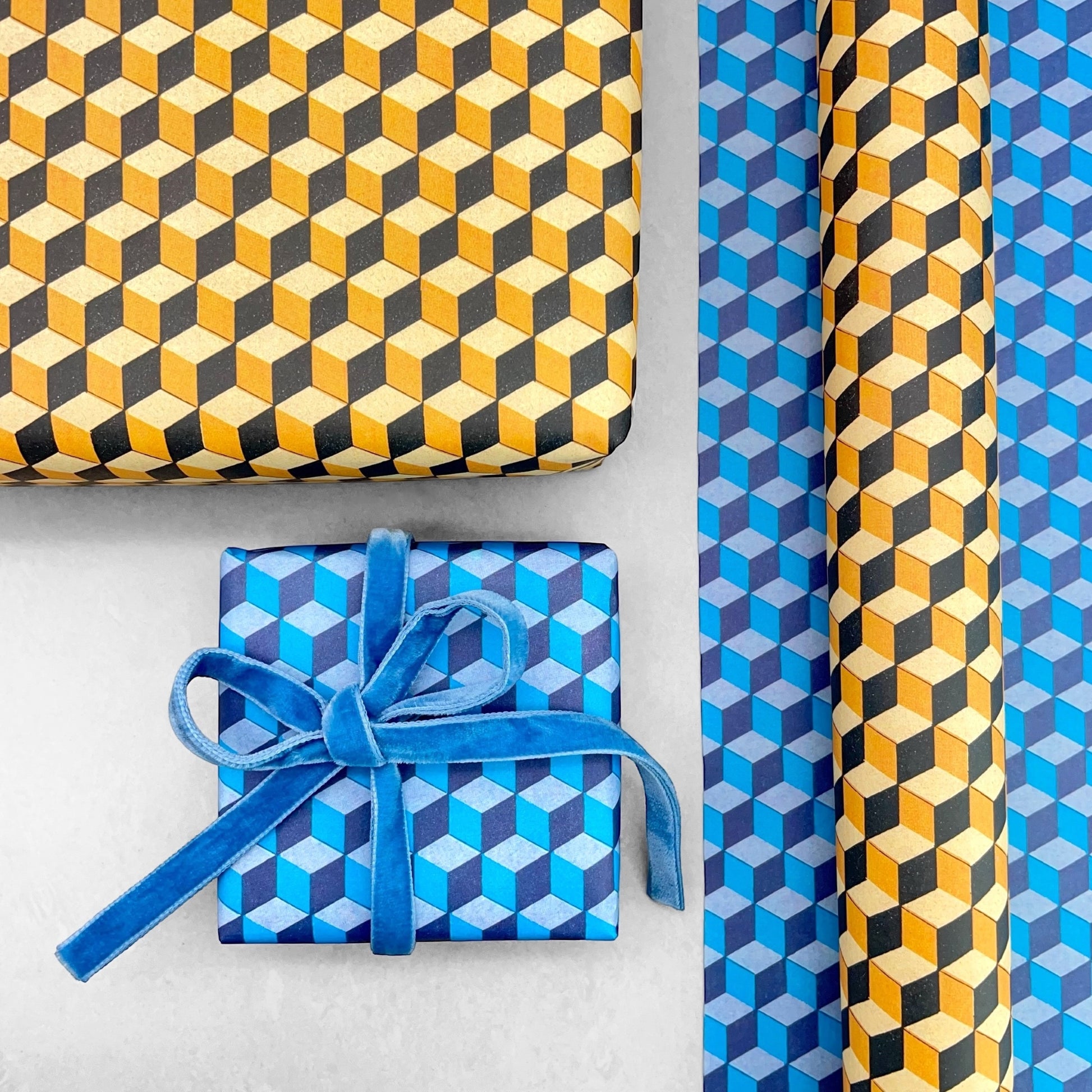 Italian patterned wrapping paper "Carta Varese" by Grafiche Tassotti. A pattern of yellow, black and lemon geometric cubes with a 3D effect.  Shown as a wrapped present alongside the same pattern in the blue version