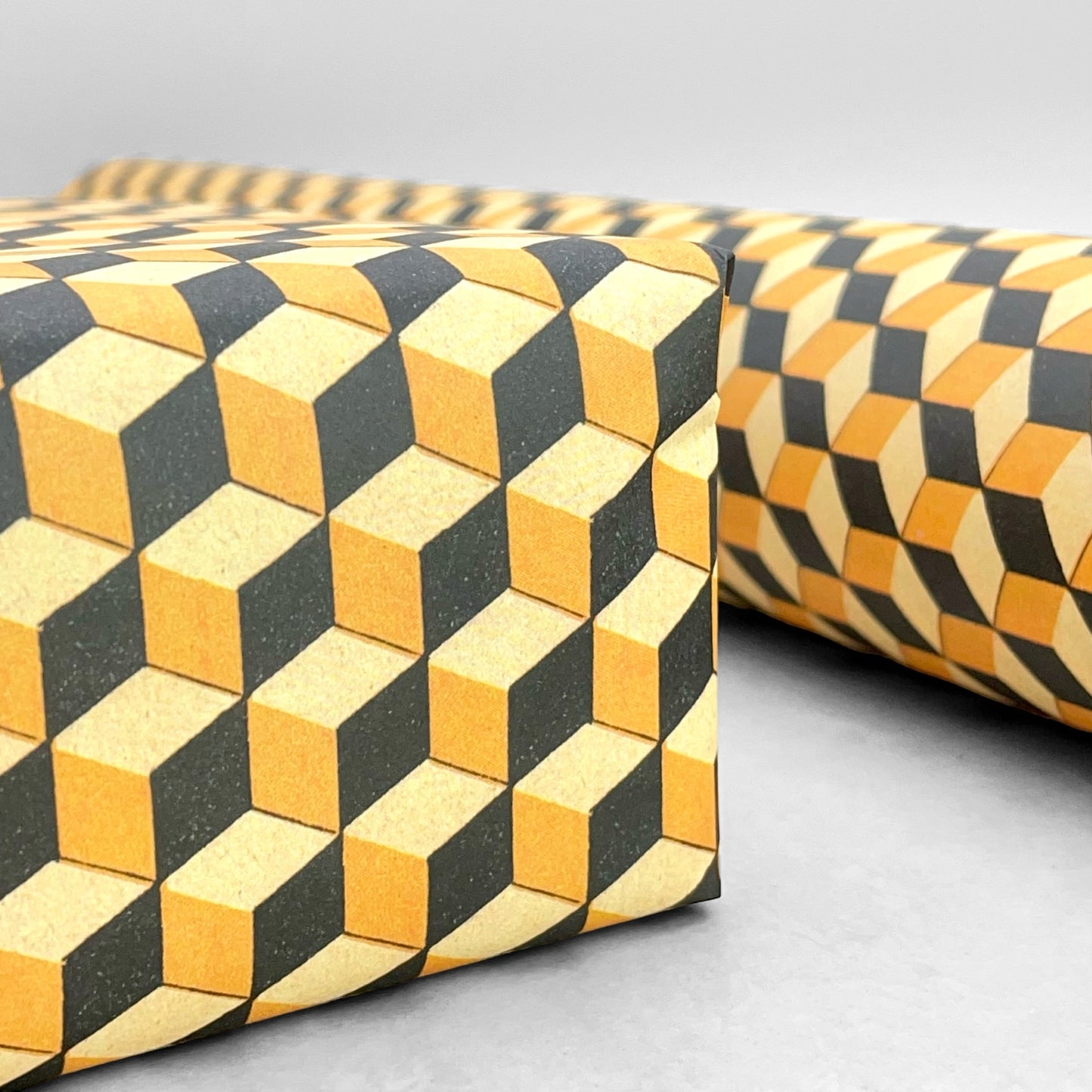 Italian patterned wrapping paper "Carta Varese" by Grafiche Tassotti. A pattern of yellow, black and lemon geometric cubes with a 3D effect. Close up