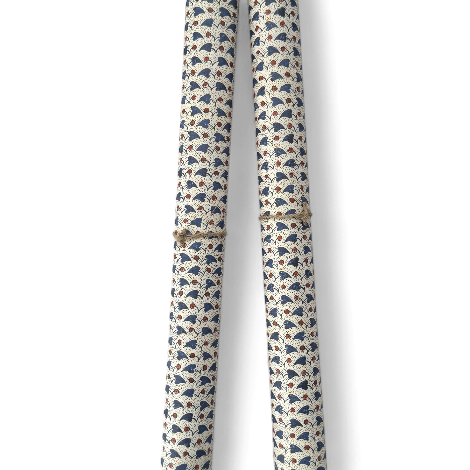 a sheet of italian wrapping paper with a blue little heart shaped leaves and red berries on white background. Pictured rolled