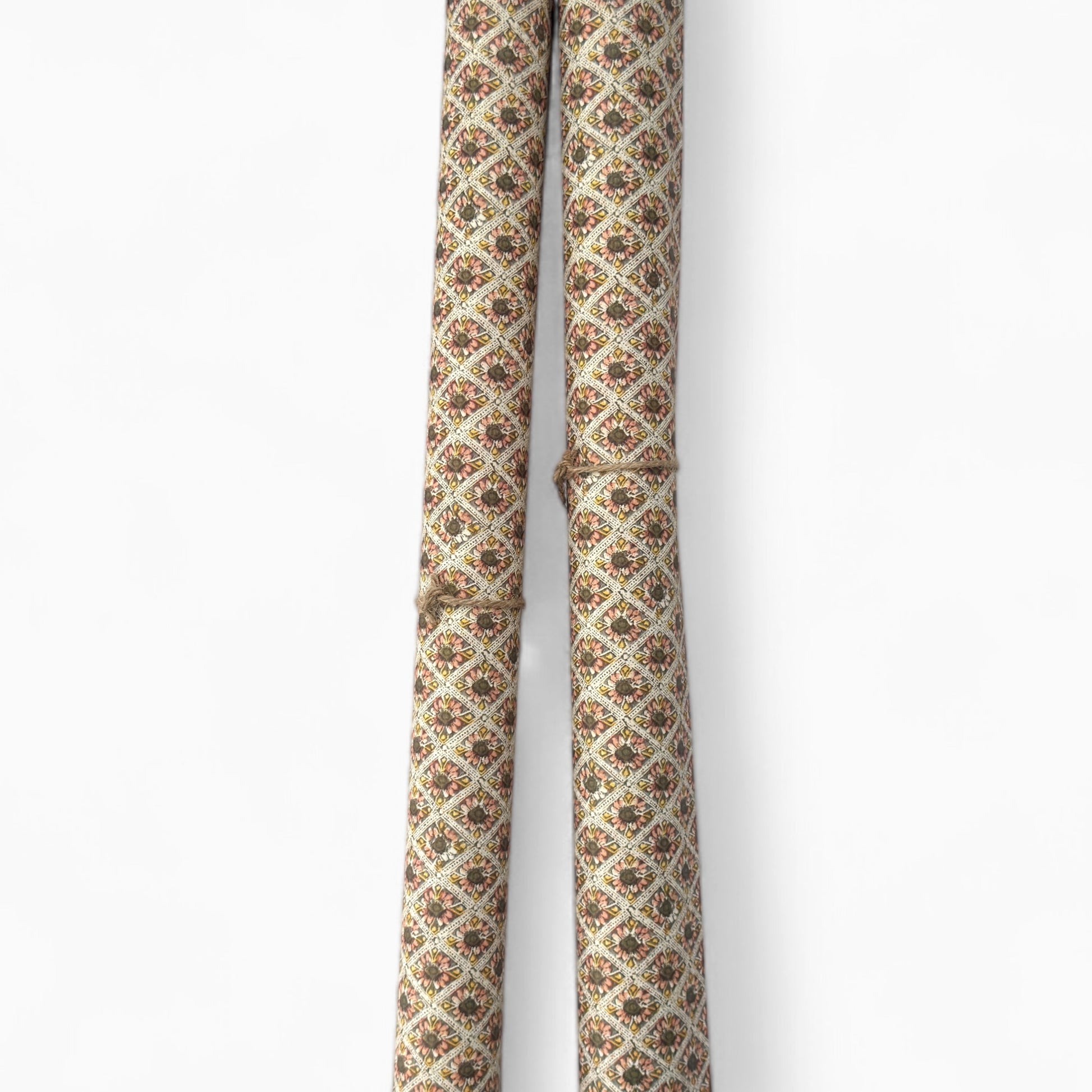 a sheet of italian wrapping paper with little flowers in a diamond grid in soft olive, pink and yellow. Pictured rolled