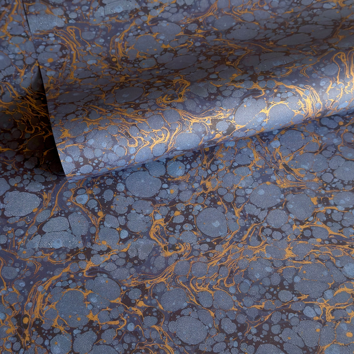a sheet of Italian wrapping paper by Tassotti with a marbled pattern in dark and light blue with gold veins