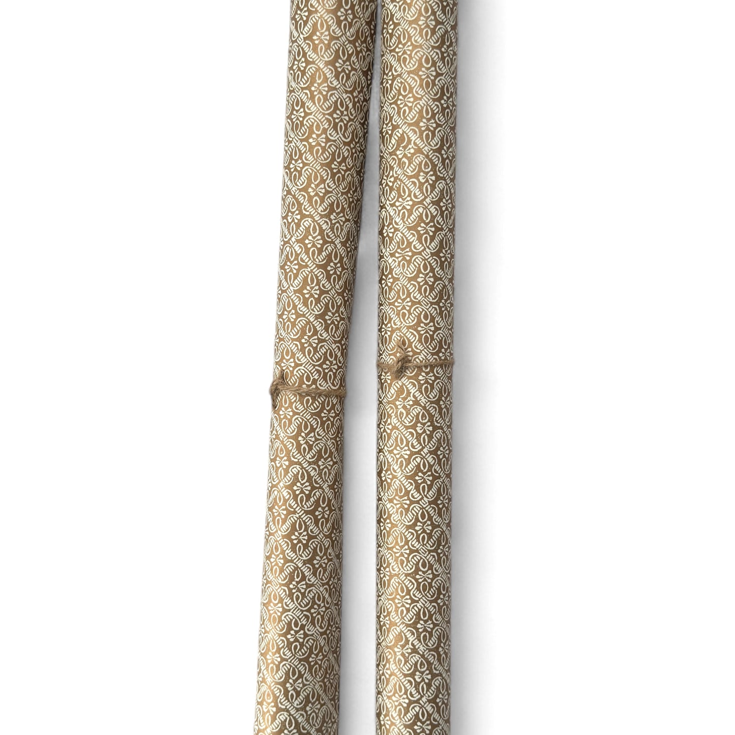 a sheet of italian wrapping paper with a decorative diamond grid in bronze gold on white. Pictured rolled