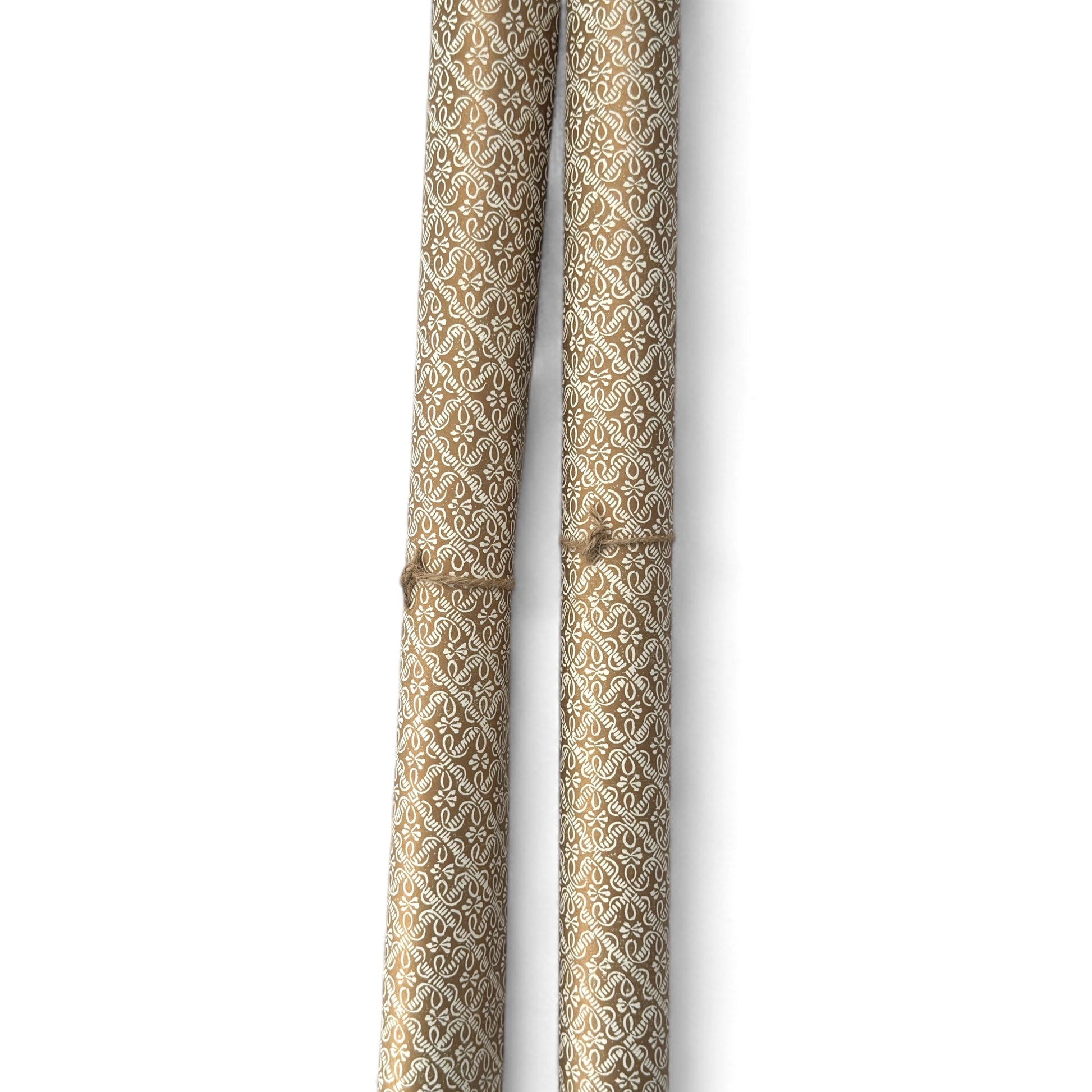 a sheet of italian wrapping paper with a decorative diamond grid in bronze gold on white. Pictured rolled