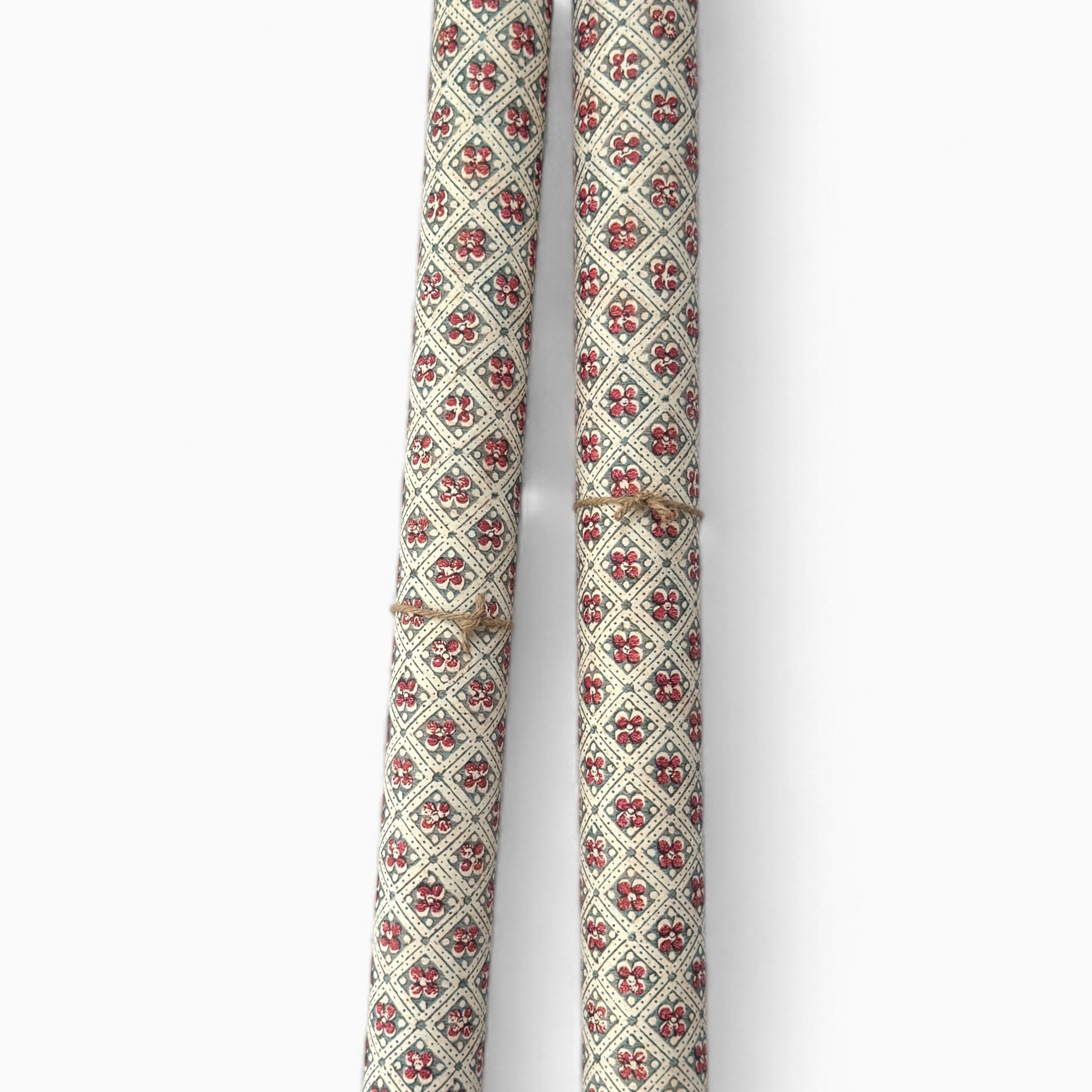 a sheet of italian wrapping paper with a little red flower in a diamond grid design in green. Pictured rolled