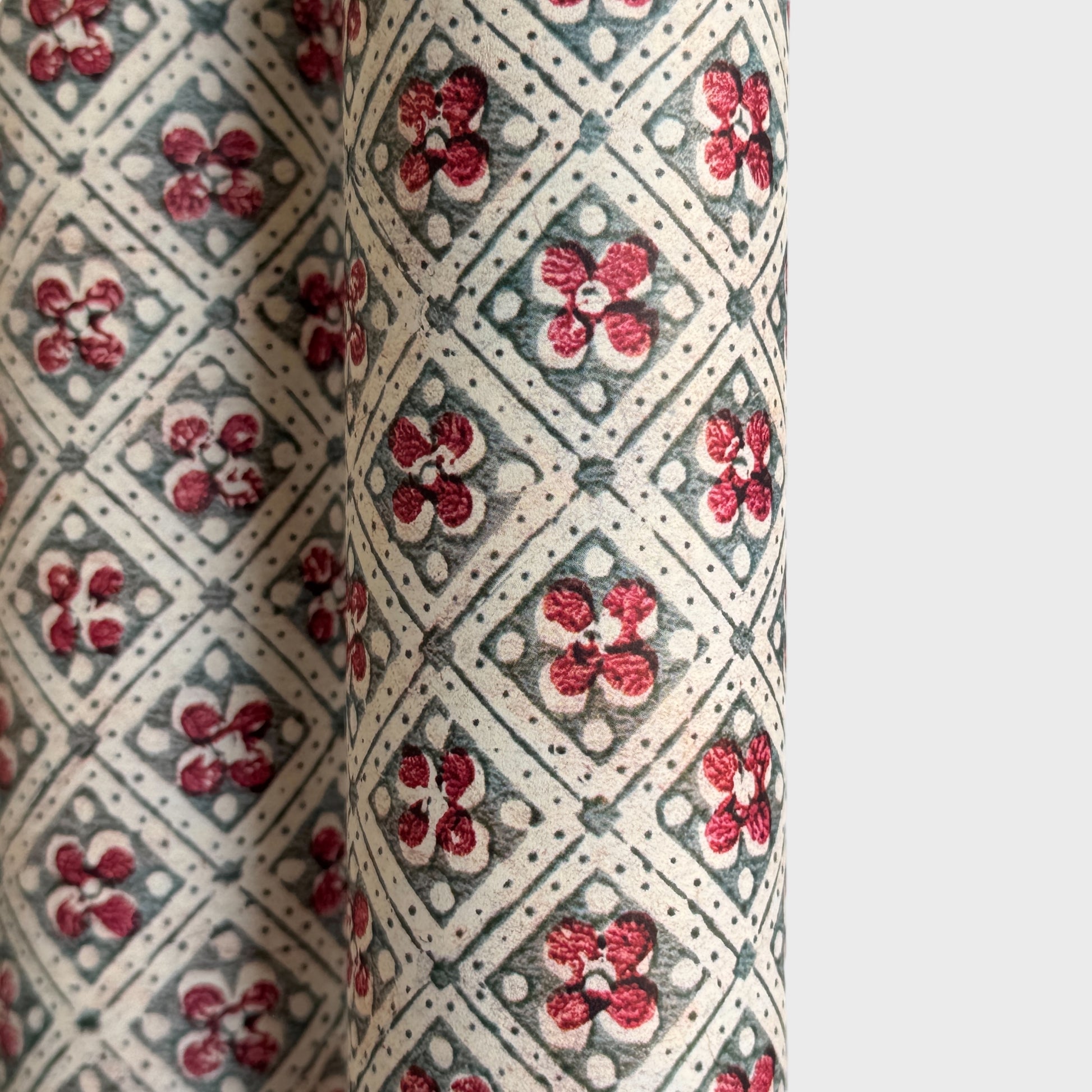 a sheet of italian wrapping paper with a little red flower in a diamond grid design in green