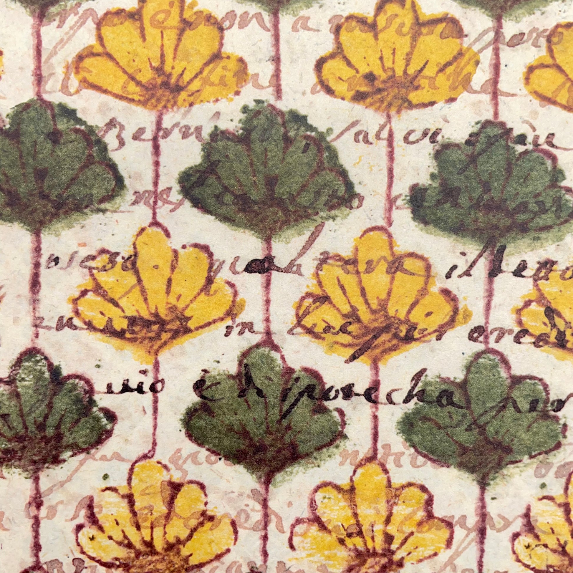 italian Remondini patterned wrapping paper by Tassotti. Repeat floral pattern with yellow and green flowers on a beige background with script writing. Close up of a present wrapped in the paper with a gold ribbon bow. Close up