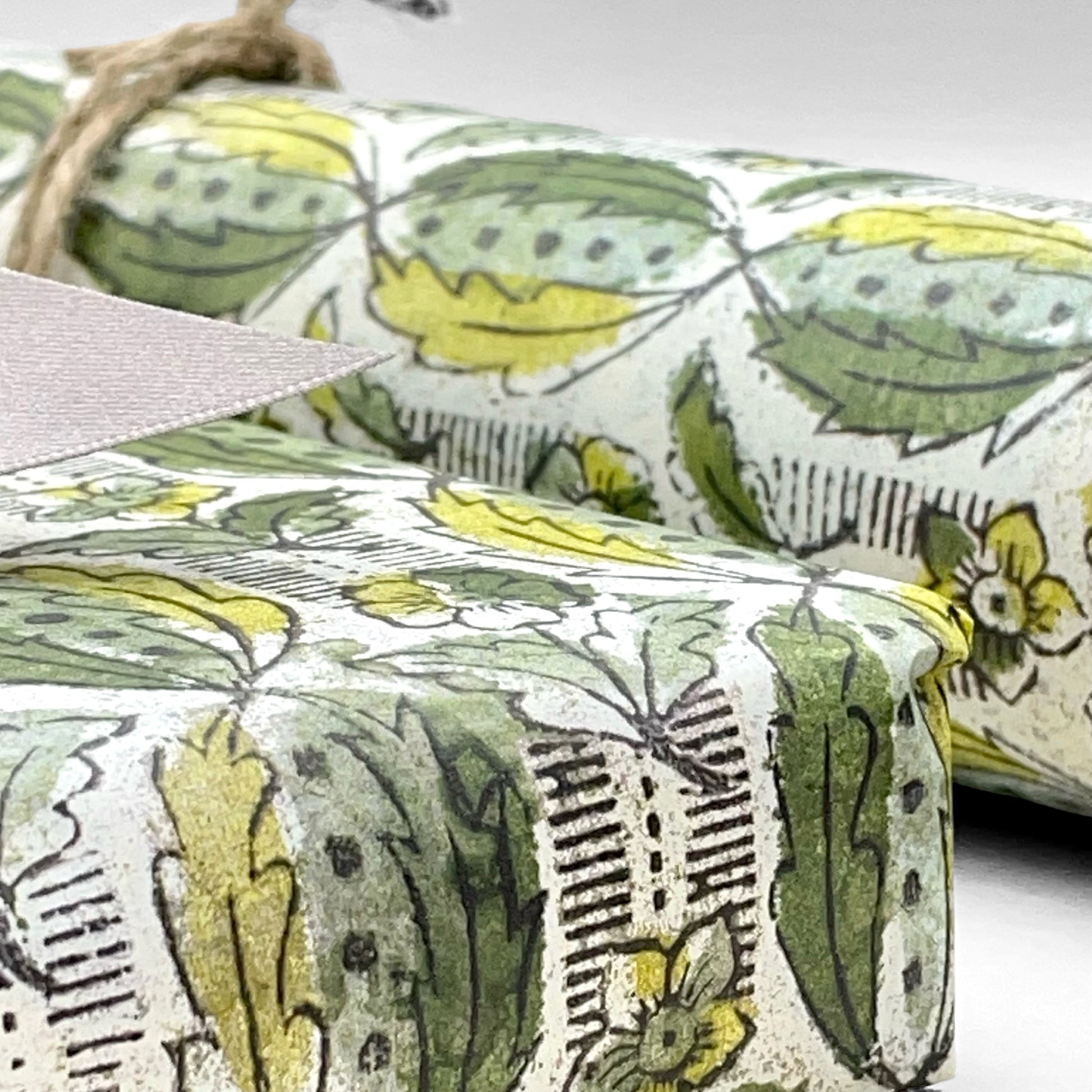 italian Remondini patterned wrapping paper by Tassotti. Block print style pattern with green leaves and flowers on a white background. Close up