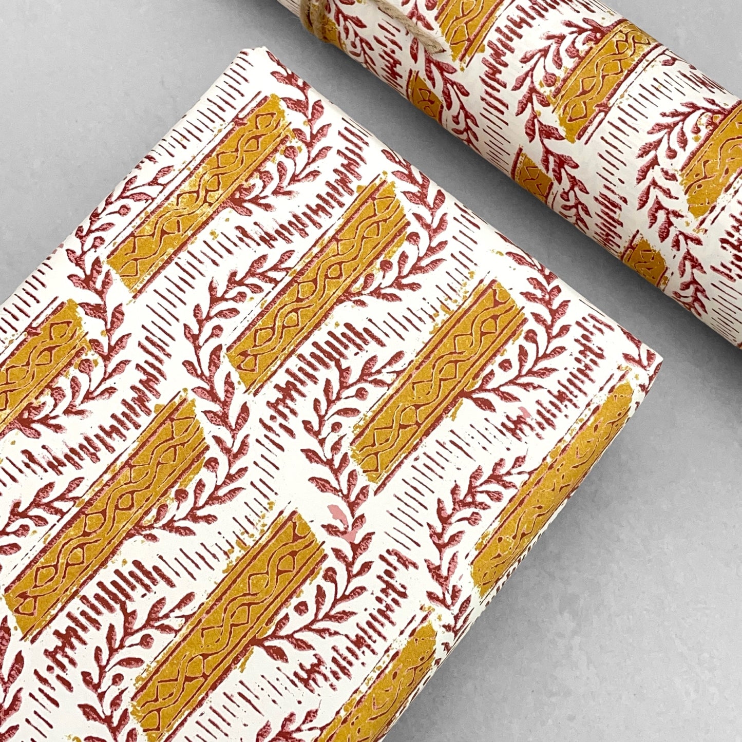 italian Remondini patterned wrapping paper by Tassotti. Mustard stripes with burgundy block printed garland on cream backdrop