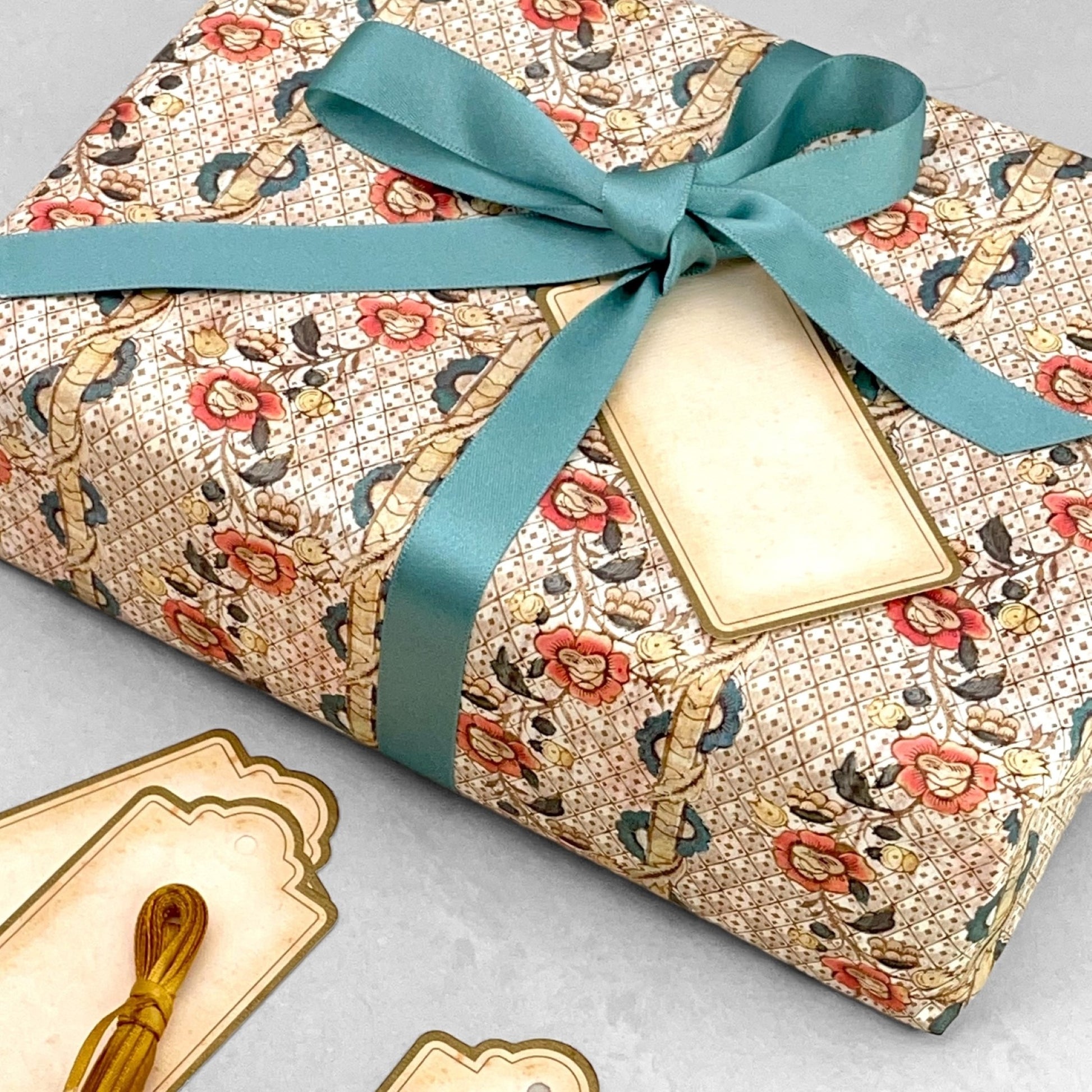Remondini Italian patterned wrapping paper by Tassotti, A detailed trellis design with flowers in taupe, rose and aqua colours. Pictured wrapped with an aqua ribbon bow and vintage gift tag