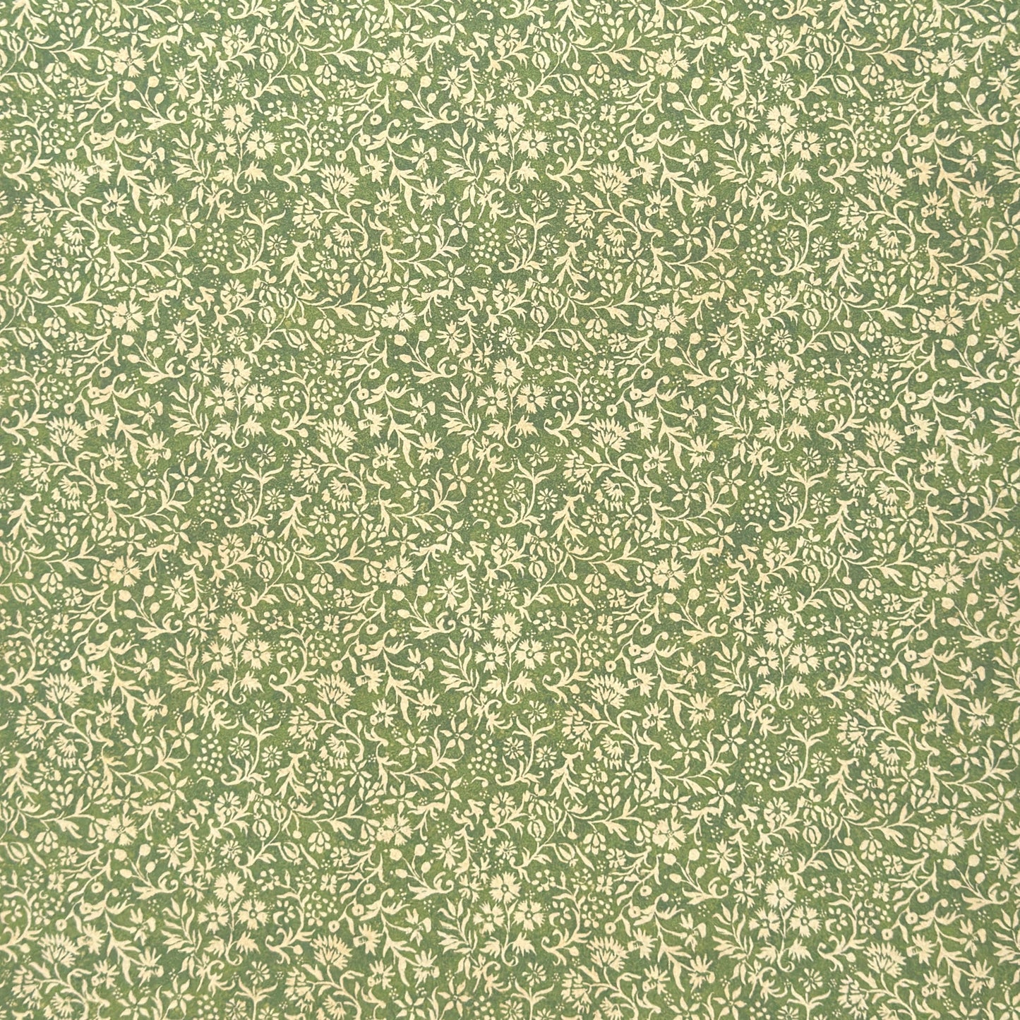 A sheet of green wrapping paper with a dense cream floral and vine pattern, shown partially unrolled on a white background.