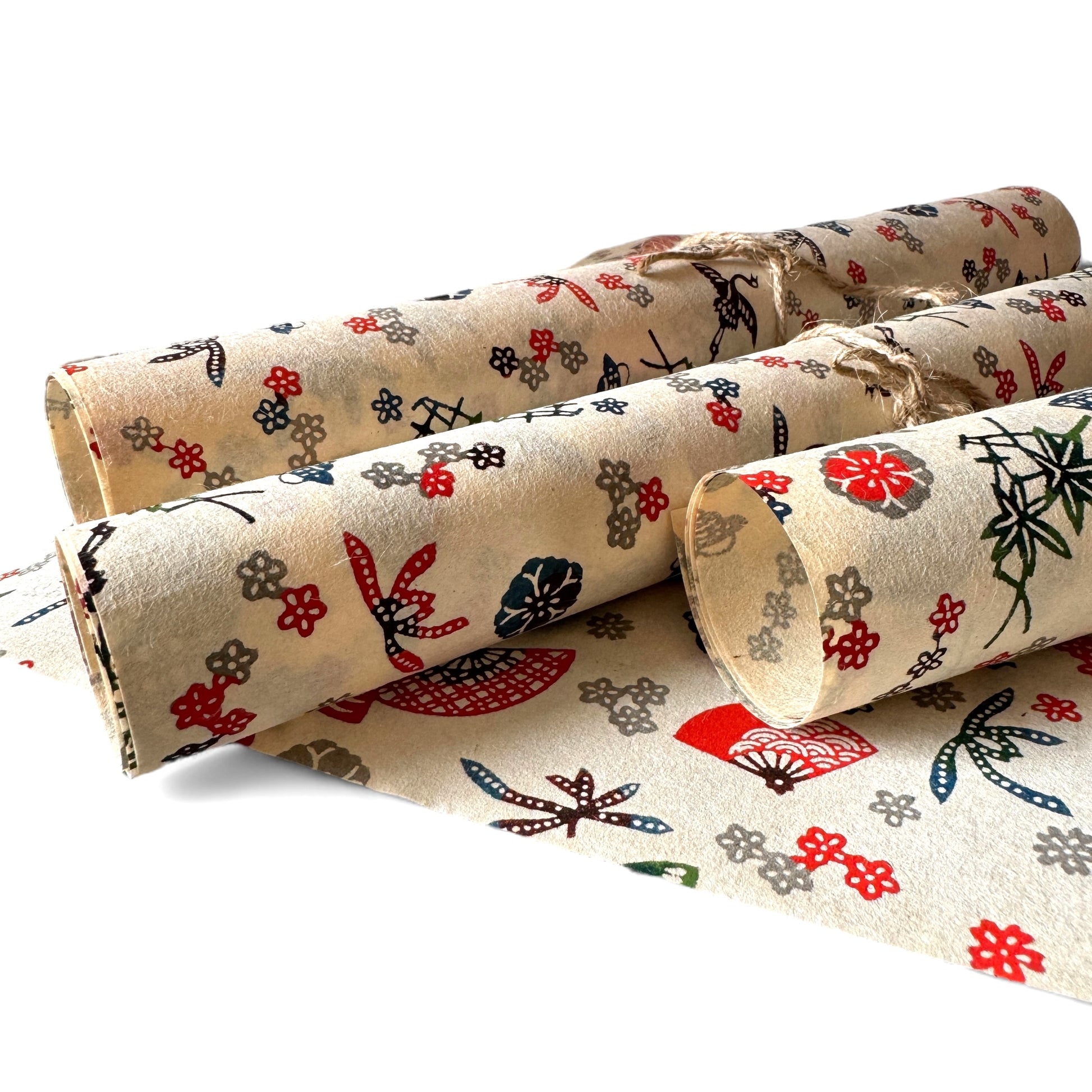 vintage katazome-shi stencil-dyed small papers from Japan. Cream paper with Japanese fan motifs in red, blue and green. Pictured rolled.