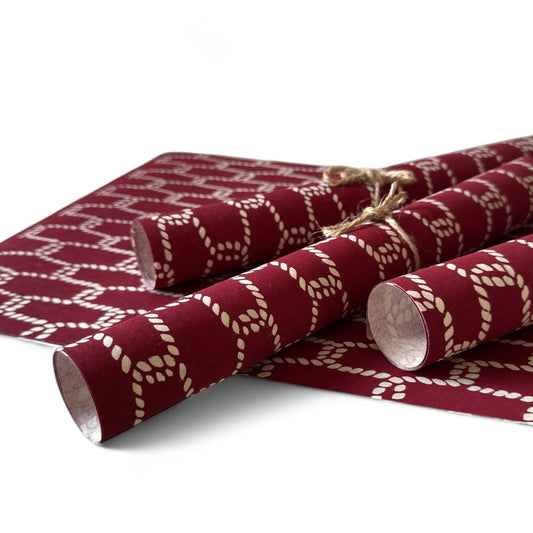vintage katazome-shi stencil-dyed small papers from Japan. burgundy paper with a cream link pattern. Pictured rolled.