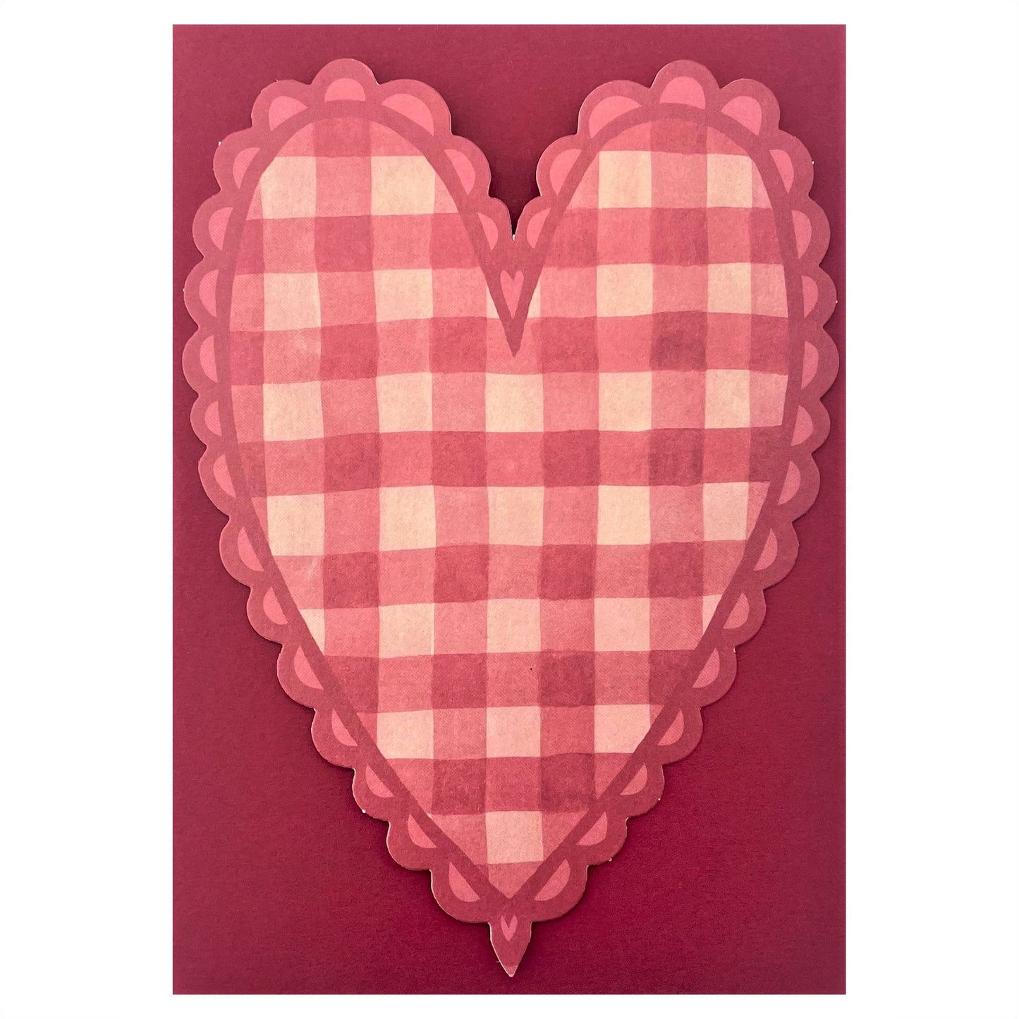 A heart shaped postcard with a red and pink gingham pattern. By Wanderlust, pictured with red envelope