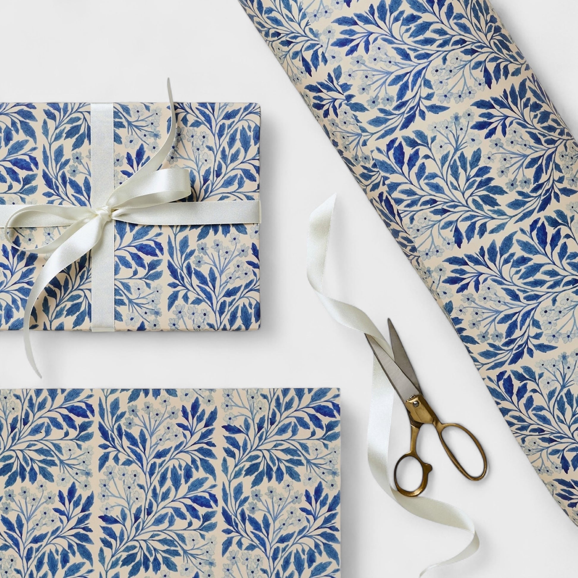 patterned paper / gift wrap with a delicate floral repeat pattern in blue on a ivory background.  By Wanderlust. Pictured wrapped