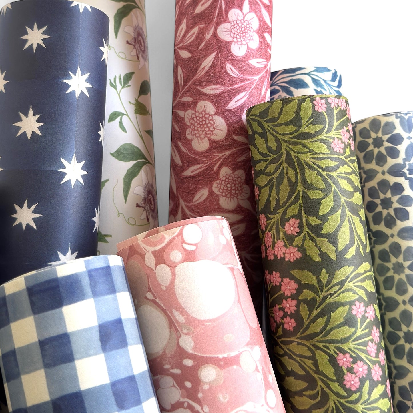 floral patterned wrapping paper in green and pink. Pictured rolled with other designs